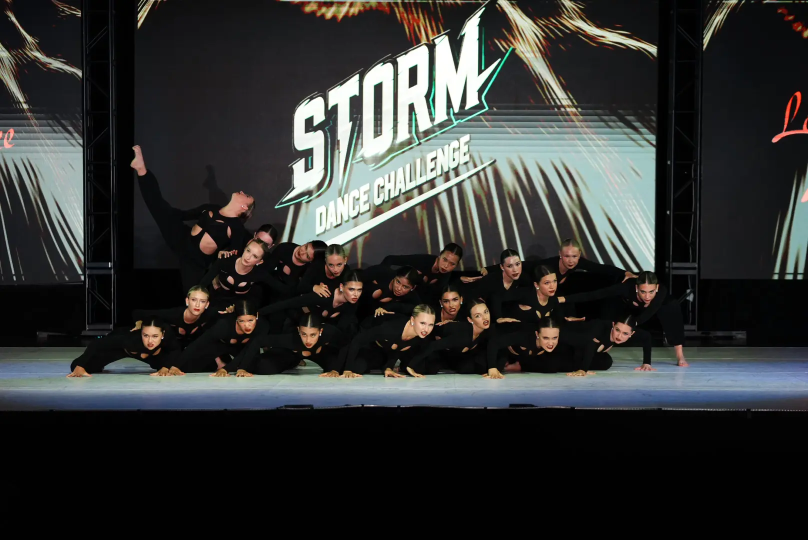 A group of performers posing together on stage under a Storm-themed backdrop.
